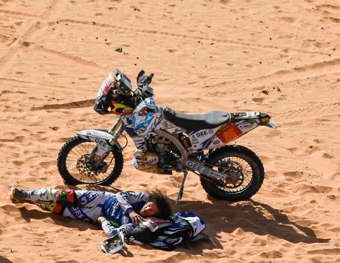 Piloto Dakar en la arena junto a su moto